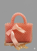 A small, peach-colored beaded handbag featuring a rounded top handle, a gold chain strap, and a loose, flowing pink satin ribbon tied at the front.